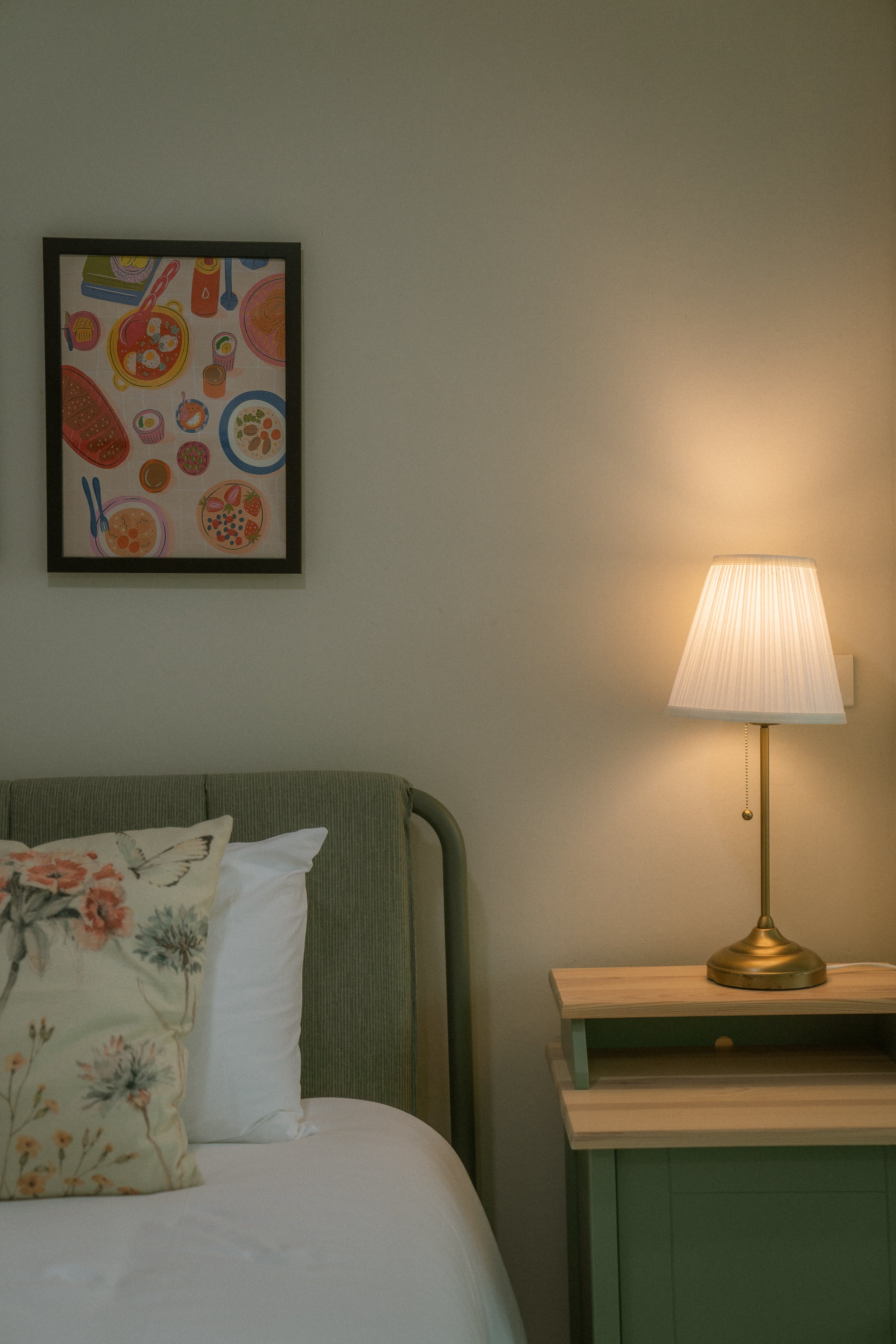 Bedside lamp, framed print and green headboard